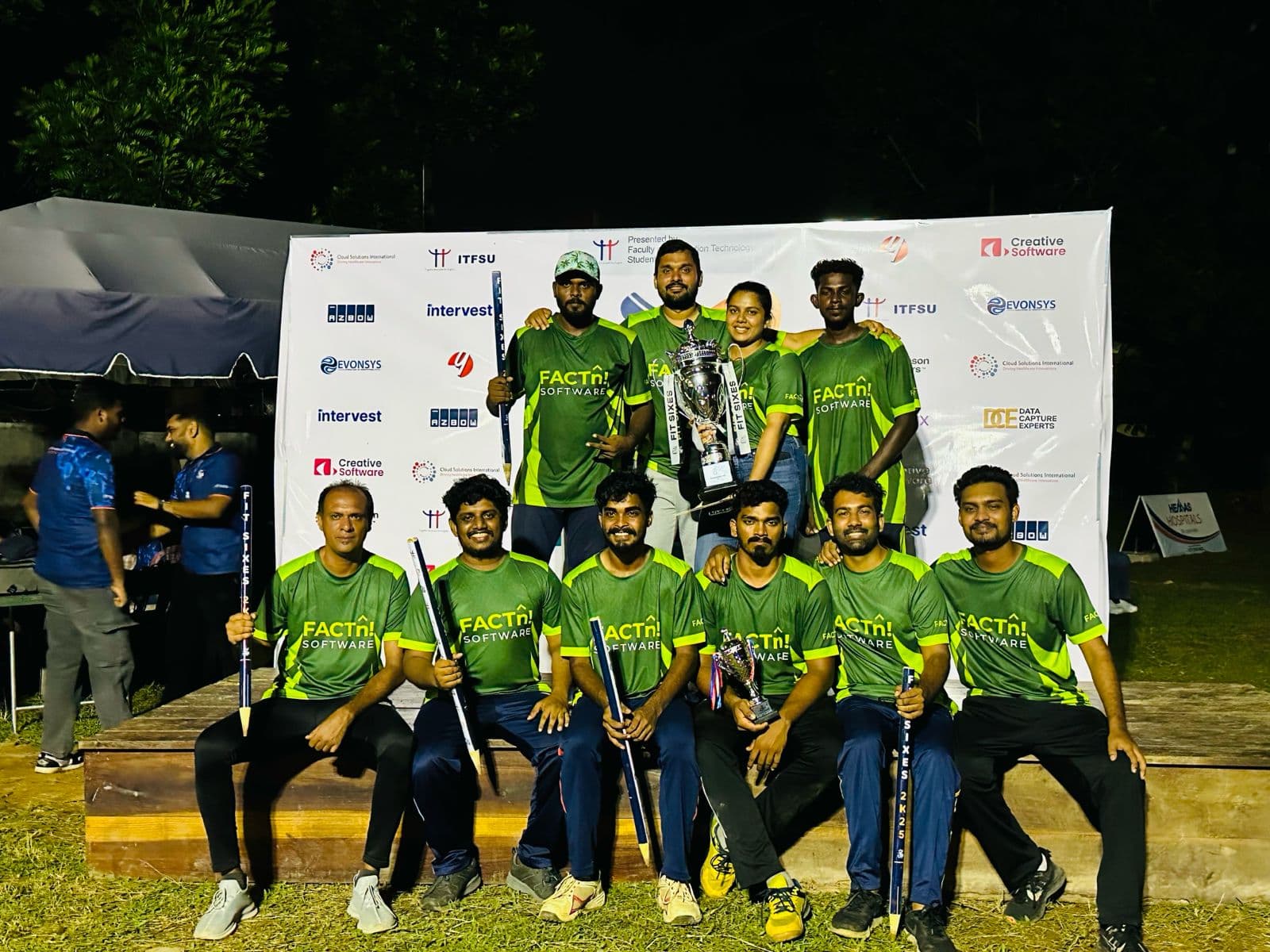 FACTn cricket team posing in front of the Fit Sixes event banner