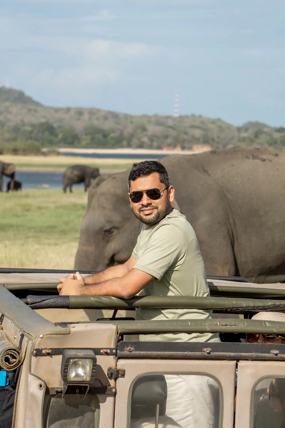 FACTn colleague smiling from a safari jeep as an elephant passes behind him
