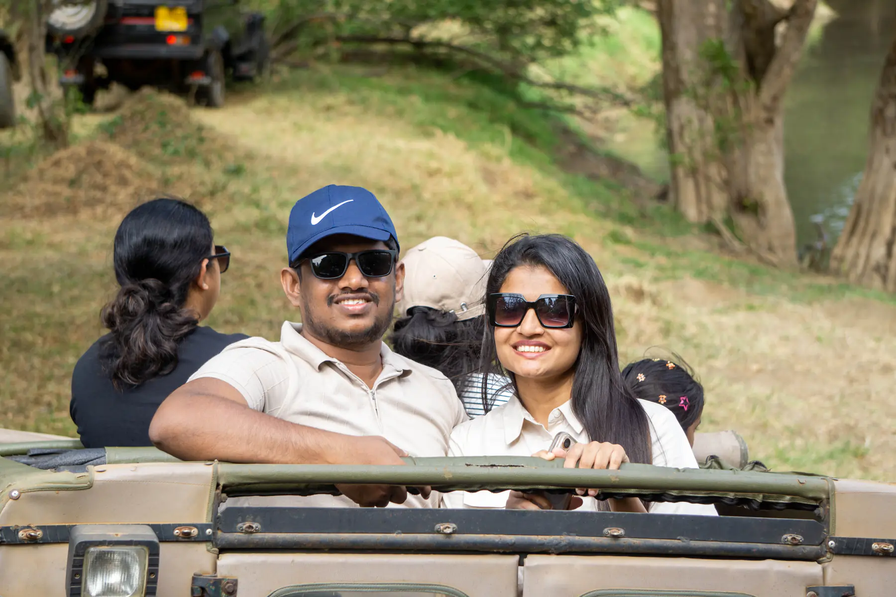 Two guests smiling together from an open-top safari jeep