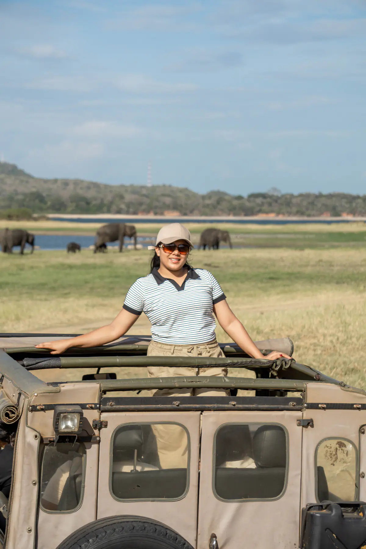 A woman posing from a safari jeep beside the Minneriya grassland