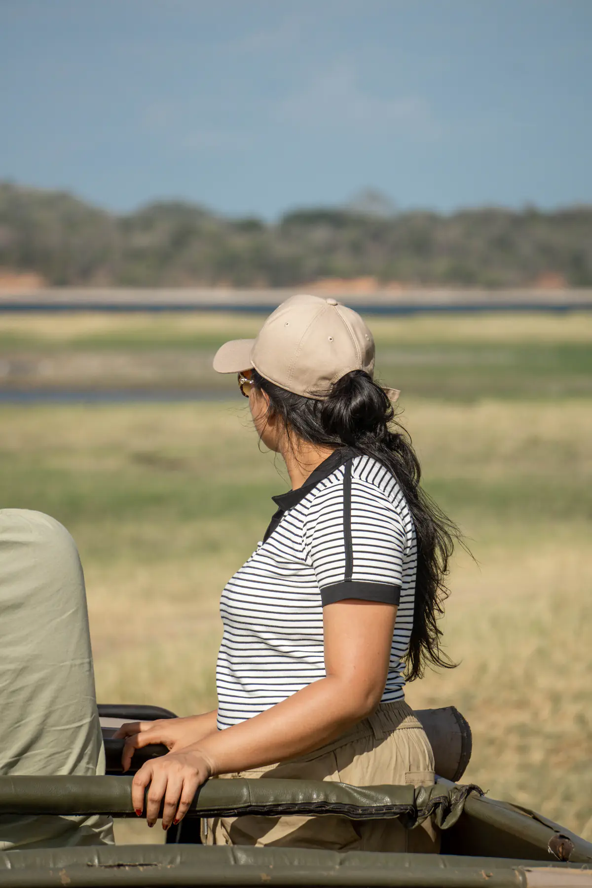 A woman looking across the open plains from a safari jeep