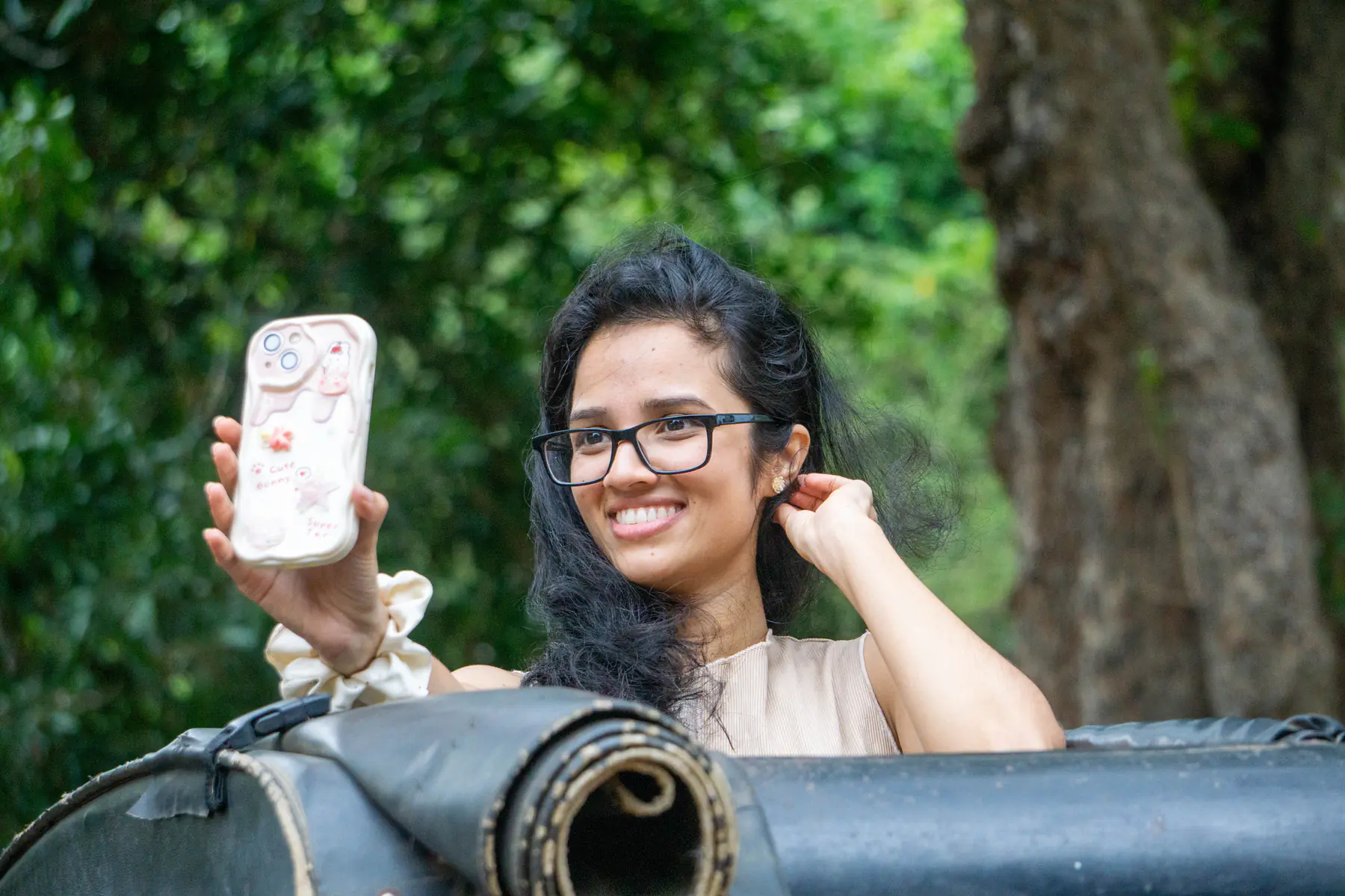 FACTn teammate smiling and holding up her phone from a safari jeep