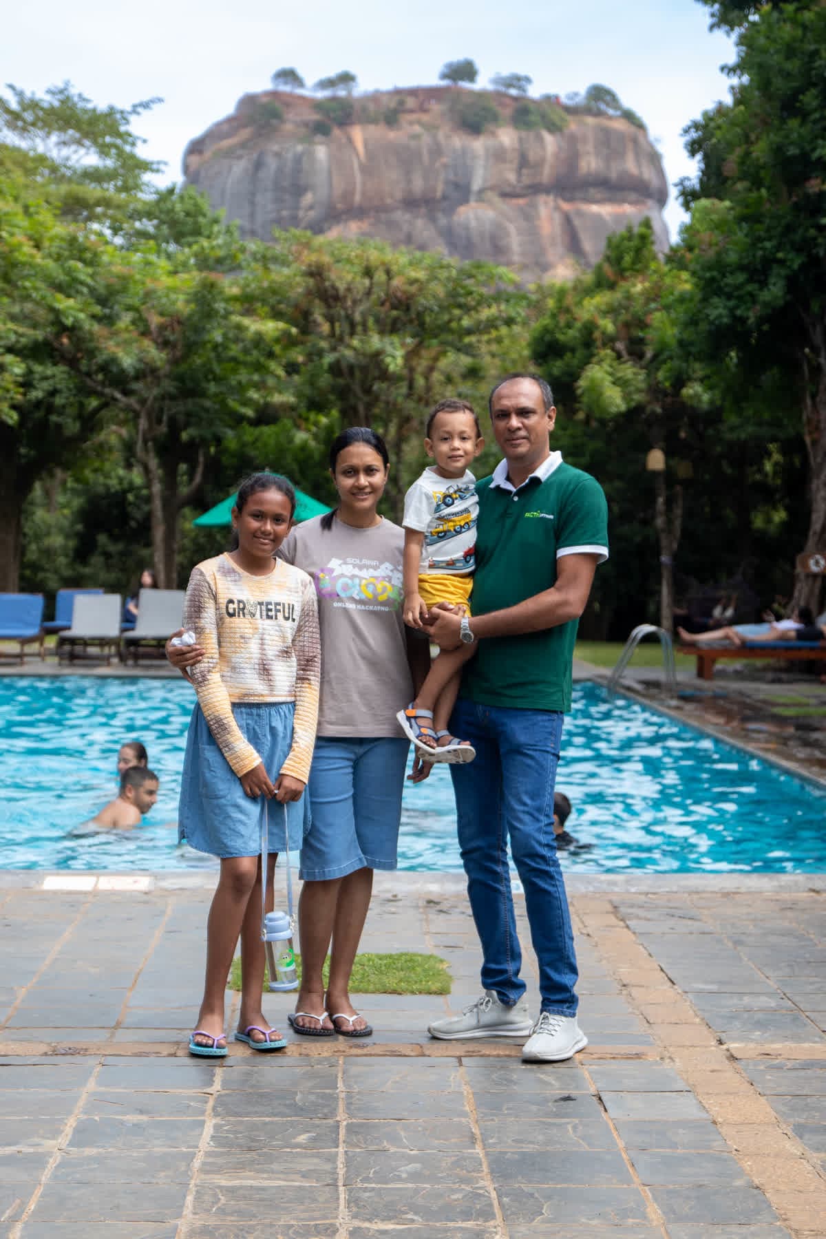 A family posing by the pool with Sigiriya Rock behind them